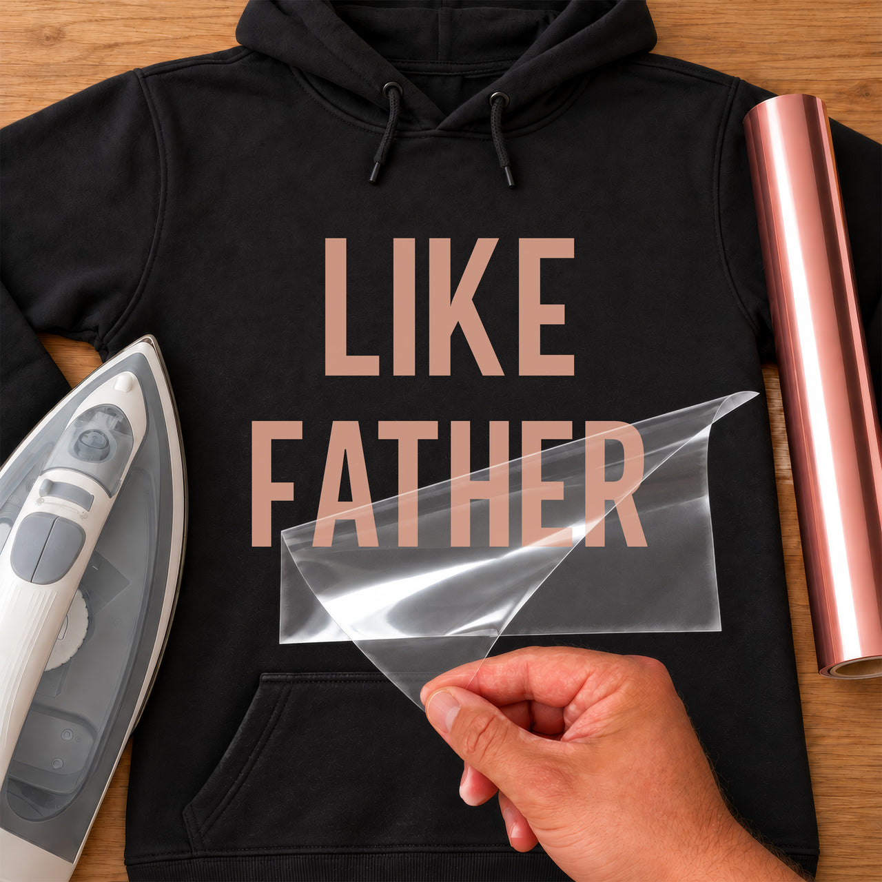 Black hoodie with rose gold 'LIKE FATHER' iron-on transfer in bold capital letters, iron and rose gold vinyl roll