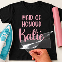 Black T-shirt with pink 'MAID OF HONOUR' and script 'Katie', personalised wedding iron-on transfer being peeled