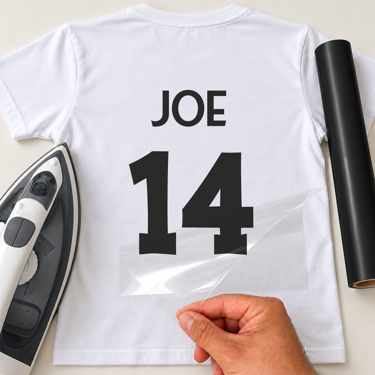 Martial Arts Gi Name Number iron-on transfer: black JOE 14 on a white T-shirt, film being peeled