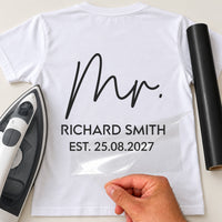 Back of white T-shirt with black 'Mr.' signature script, 'RICHARD SMITH' and 'EST. 25.08.2027', iron and vinyl roll