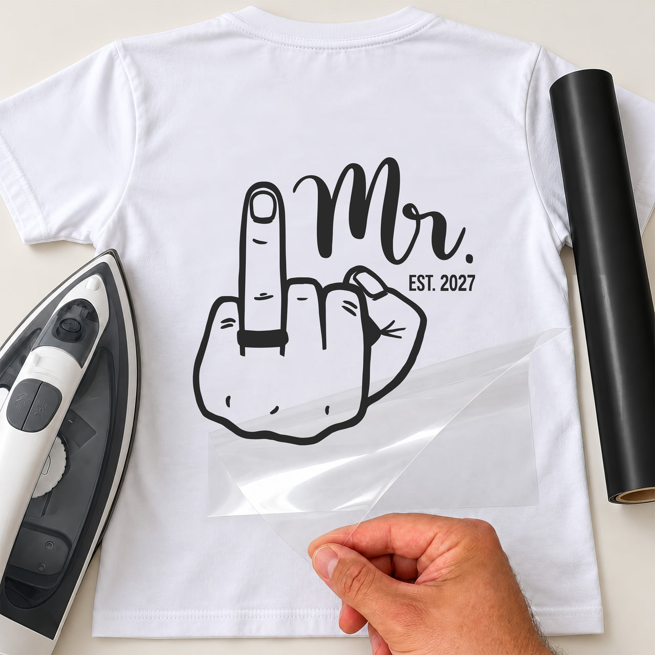 Back of white T-shirt with black 'Mr.' script, 'EST. 2027' and hand line art with ring on raised finger, iron and vinyl roll