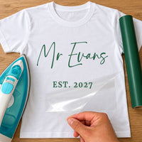 Mr Surname iron-on transfer: green script Mr Evans EST. 2027 on a white T-shirt, film being peeled