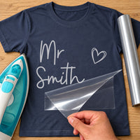 Navy T-shirt with silver script 'Mr Smith' and an outline heart, carrier film being peeled off - iron-on vinyl transfer