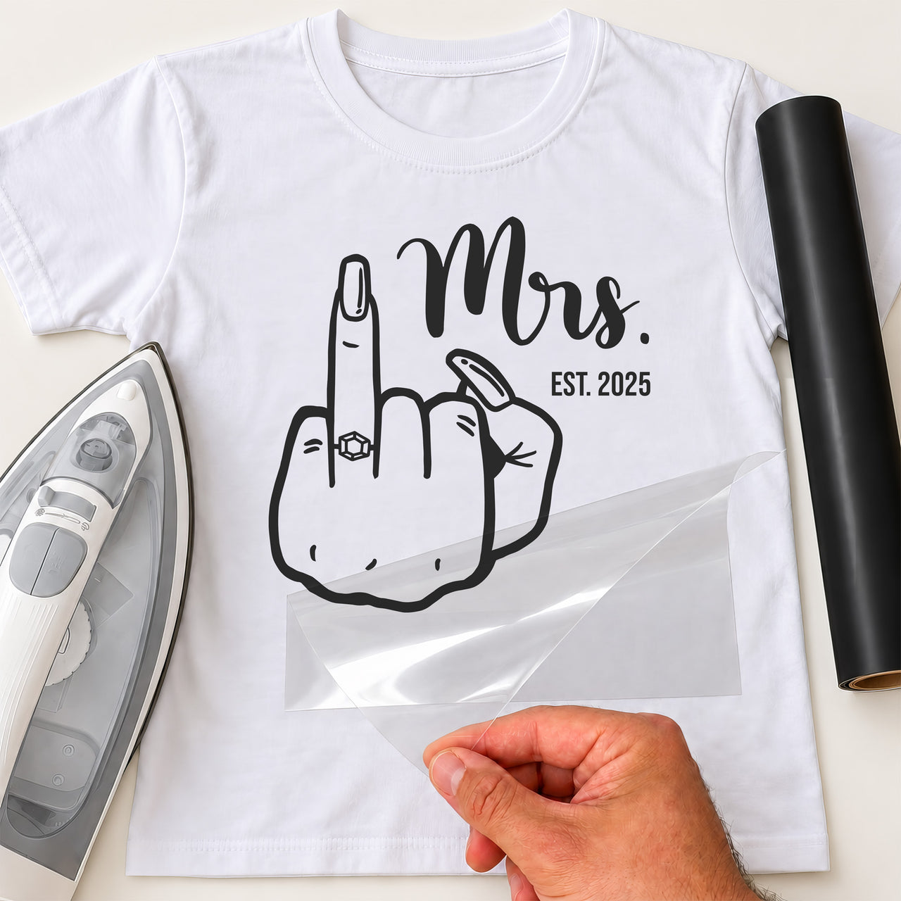 White T-shirt with black 'Mrs.' script, 'EST. 2025' and hand line art with ring on raised finger, iron and black vinyl roll