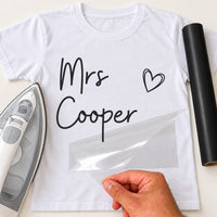 White T-shirt with black 'Mrs Cooper' script and a heart, carrier film being peeled off - iron-on vinyl transfer