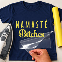 Yellow iron-on transfer with the words Namaste Bitches on a navy T-shirt, with an iron and a hand peeling the film