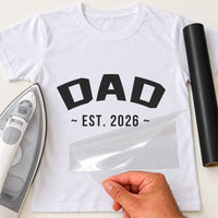 White T-shirt with black arched 'DAD' and '~ EST. 2026 ~' iron-on transfer, iron and black vinyl roll