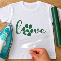 White T-shirt with green iron-on vinyl script 'love' with a paw print as the o, iron beside