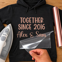 Anniversary metallic iron-on: rose gold TOGETHER SINCE 2016 Alex & Sam on a black hoodie, film being peeled