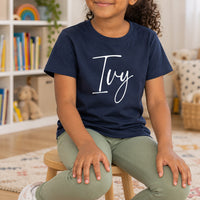 Personalised Baby Bodysuit Name Iron-On Transfer, shown on a navy kids t-shirt