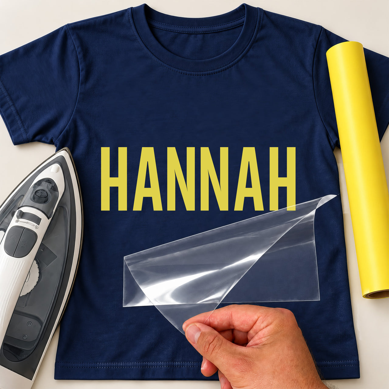 Personalised Beautician Name iron-on transfer: yellow HANNAH on a navy T-shirt, film being peeled