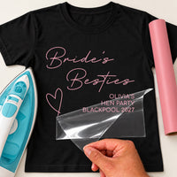 Black T-shirt, pink 'Bride's Besties' and 'OLIVIA'S HEN PARTY BLACKPOOL 2027', film peeled off - iron-on vinyl transfer