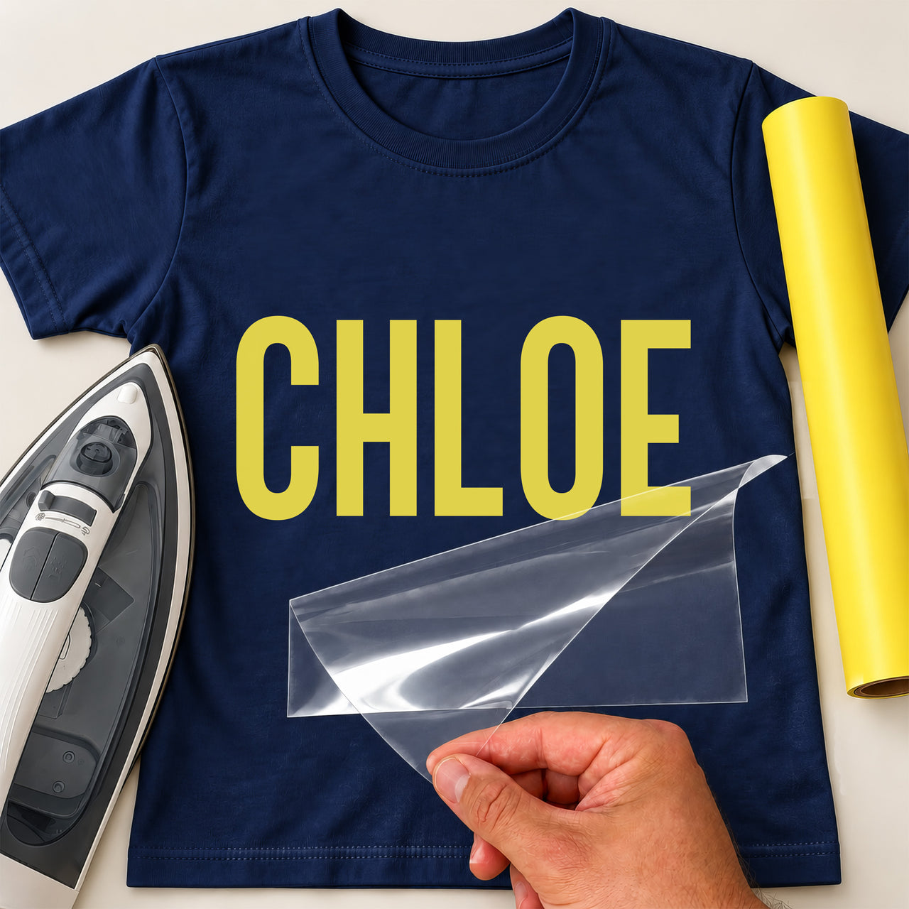 Personalised Carpenter Name iron-on transfer: yellow CHLOE on a navy T-shirt, film being peeled