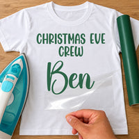 Christmas Eve Crew iron-on transfer: green CHRISTMAS EVE CREW Ben on a white T-shirt, film being peeled