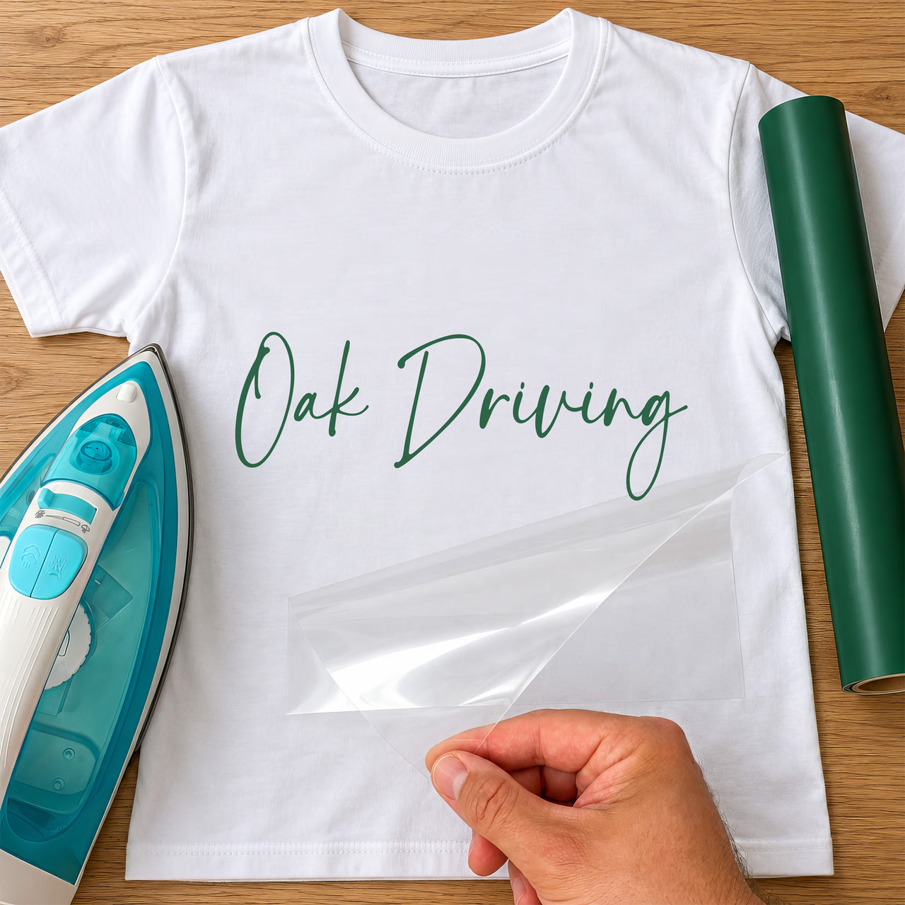 Driving Instructor Name iron-on transfer: green script Oak Driving on a white T-shirt, film being peeled