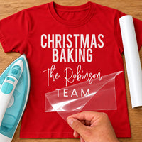 Christmas Baking Team iron-on transfer: white CHRISTMAS BAKING The Robinson TEAM on a red T-shirt, film being peeled