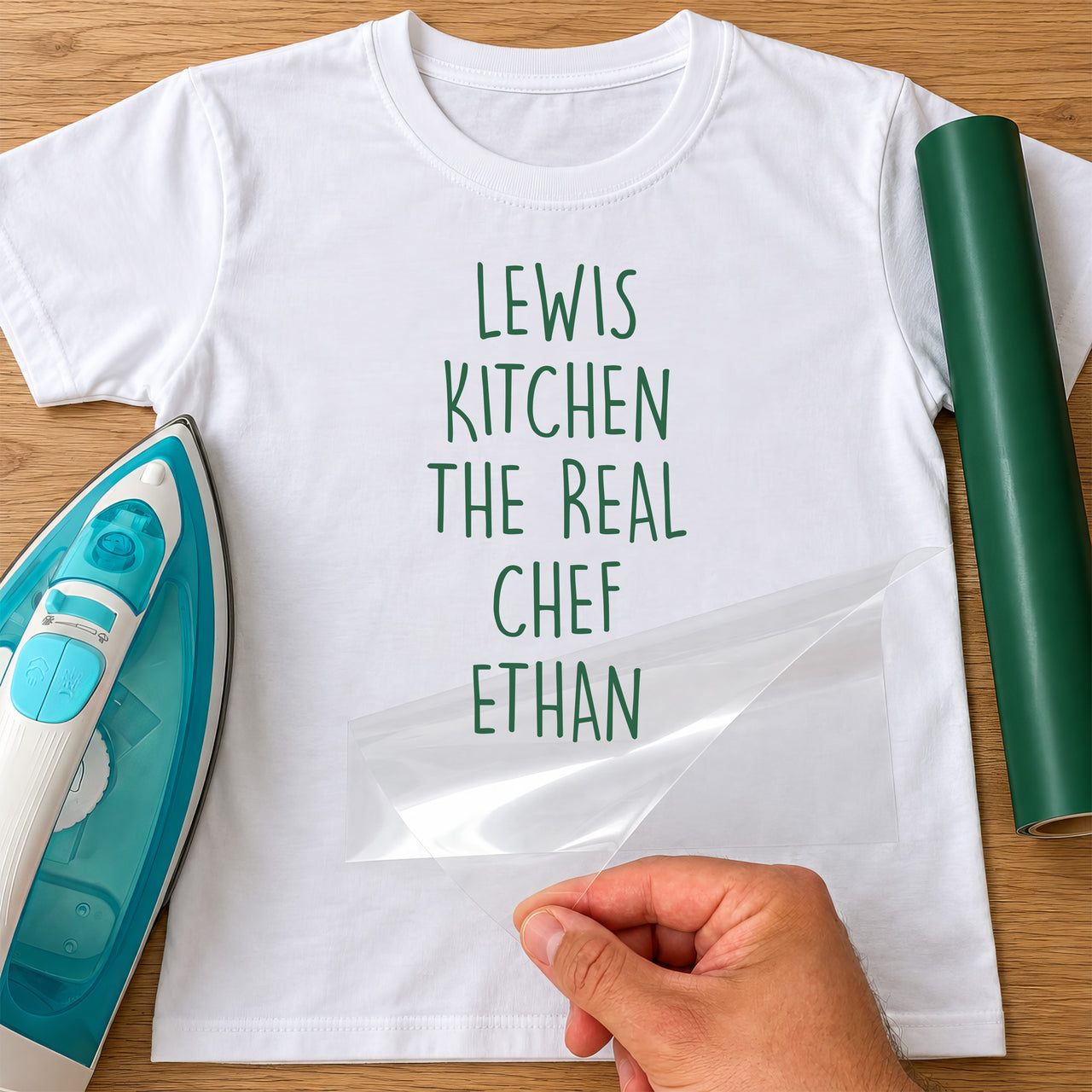 Real Chef name iron-on transfer: green LEWIS KITCHEN THE REAL CHEF ETHAN on a white T-shirt, film being peeled