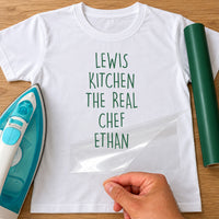 Real Chef name iron-on transfer: green LEWIS KITCHEN THE REAL CHEF ETHAN on a white T-shirt, film being peeled
