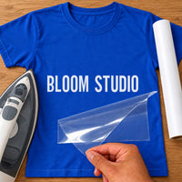 Florist Name iron-on transfer: white BLOOM STUDIO on a royal blue T-shirt, film being peeled