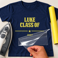 Graduation 2026 iron-on transfer: yellow LUKE CLASS OF 2027 on a navy T-shirt, film being peeled