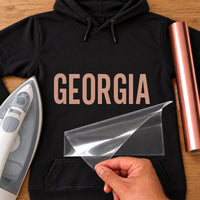 Nail Tech Name iron-on transfer: rose gold GEORGIA on a black hoodie, film being peeled