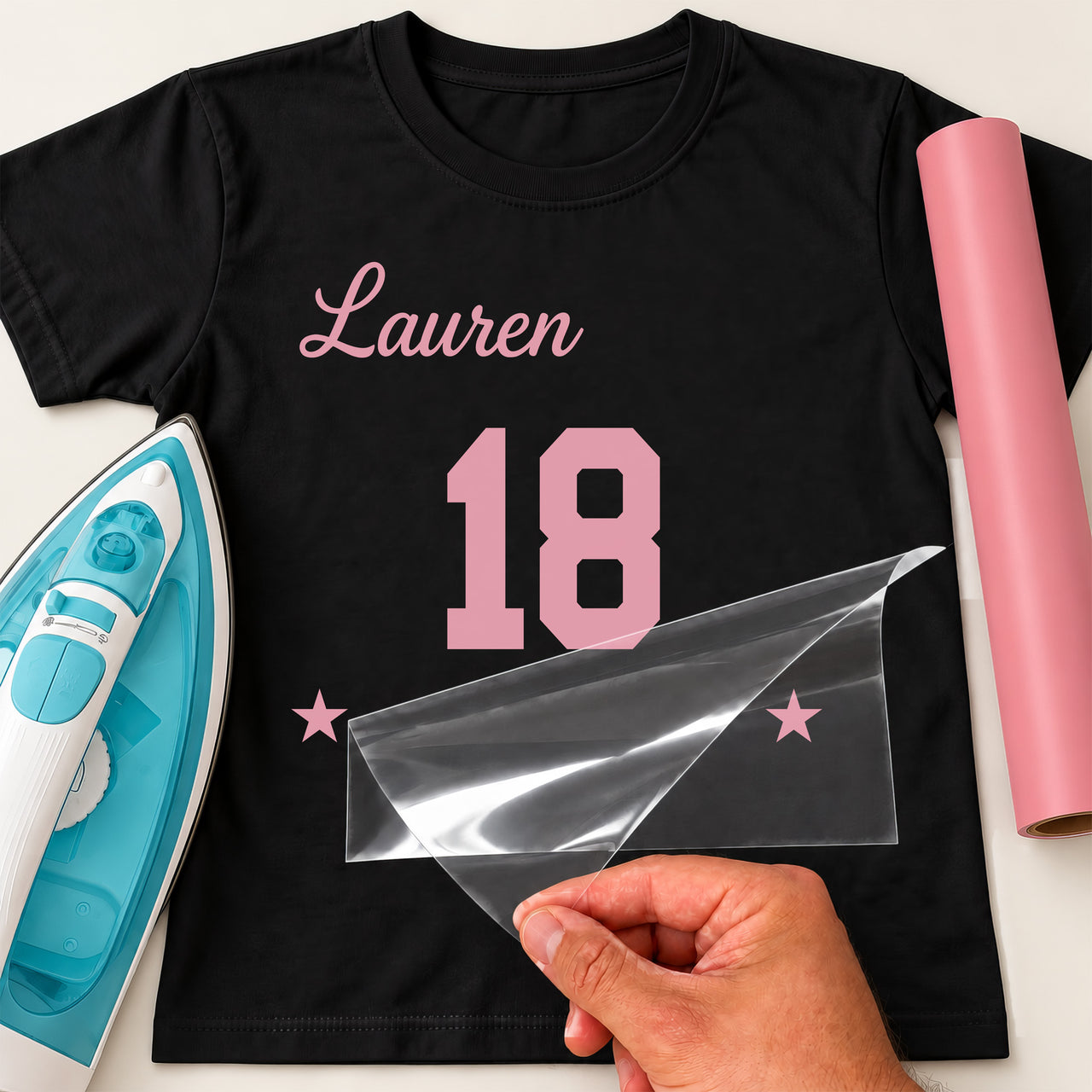 Black T-shirt with pink 'Lauren' script, varsity '18' and stars iron-on transfer, iron and pink vinyl roll
