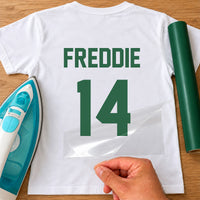 Netball Dress Name Number iron-on transfer: green FREDDIE 14 on a white T-shirt, film being peeled