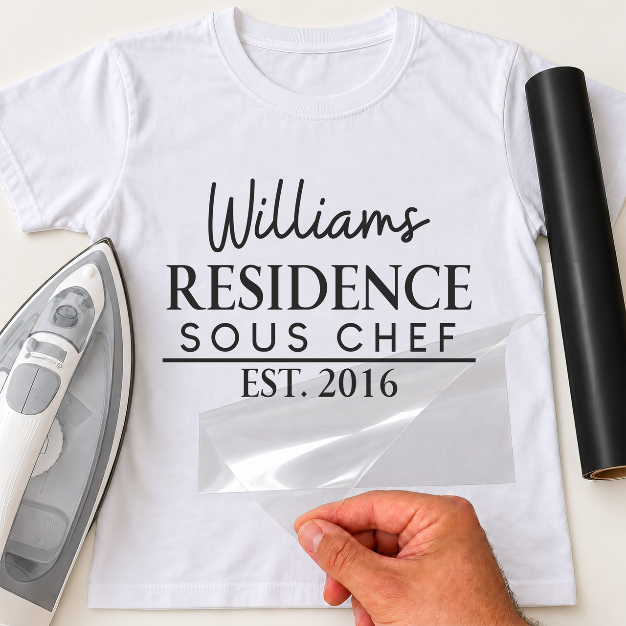 Sous Chef residence iron-on transfer: black Williams RESIDENCE SOUS CHEF EST. 2016 on a white T-shirt, film being peeled