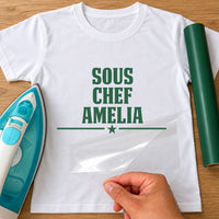 Sous Chef name iron-on transfer: green SOUS CHEF AMELIA with a star on a white T-shirt, film being peeled