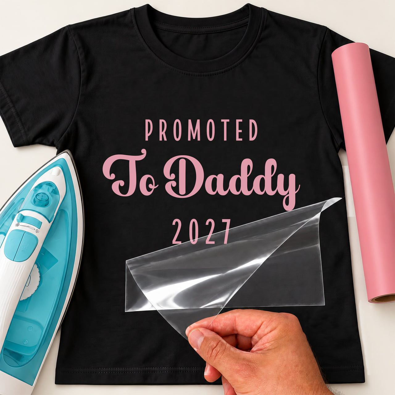 Black T-shirt with pink 'PROMOTED To Daddy 2027' iron-on transfer, capitals and script, iron and pink vinyl roll