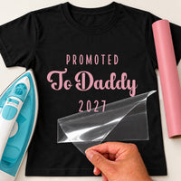 Black T-shirt with pink 'PROMOTED To Daddy 2027' iron-on transfer, capitals and script, iron and pink vinyl roll