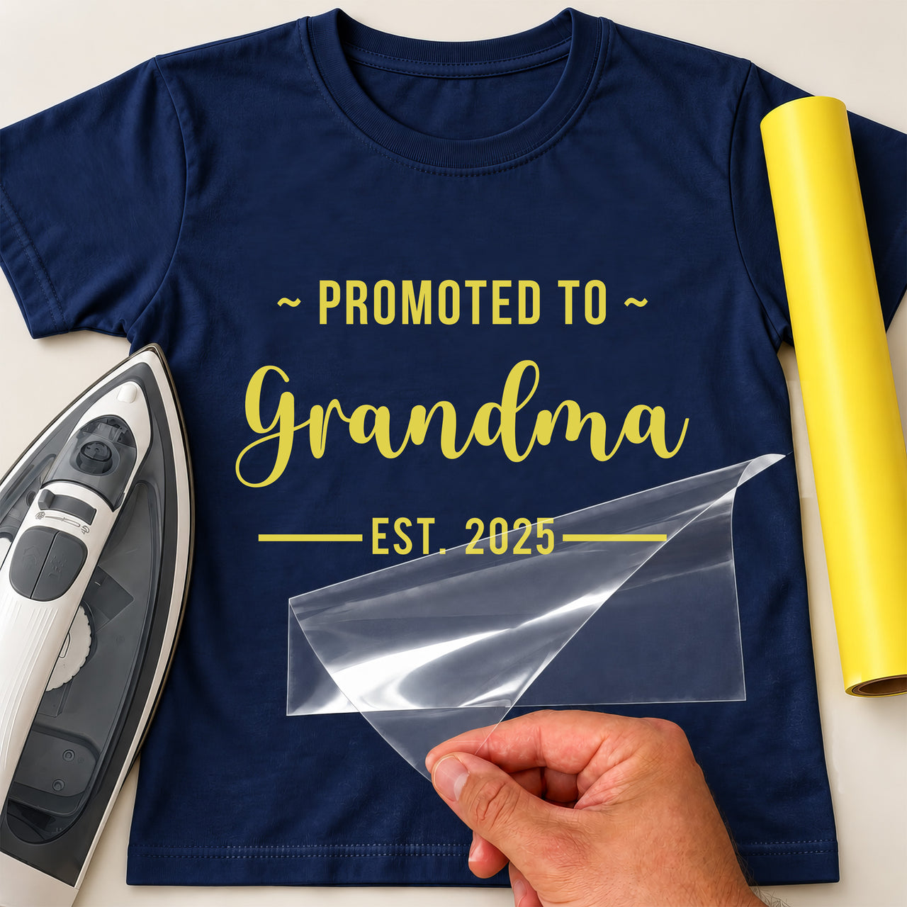 Navy T-shirt mockup with yellow "PROMOTED TO Grandma EST. 2025", the name word in script, beside an iron