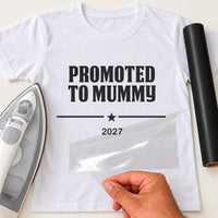 White T-shirt with black 'PROMOTED TO MUMMY' iron-on transfer, star divider and year '2027', iron and black vinyl roll
