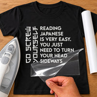 Black T-shirt with white iron-on transfer of vertical sideways lettering and a joke about reading, film being peeled