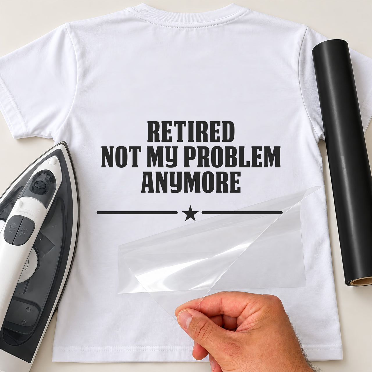 Back of white T-shirt with black 'RETIRED NOT MY PROBLEM ANYMORE' bold capitals and star divider, iron and black vinyl roll