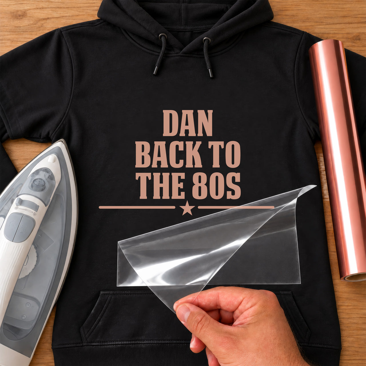 Retro 80s Neon Name iron-on transfer: rose gold DAN BACK TO THE 80S on a black hoodie, film being peeled