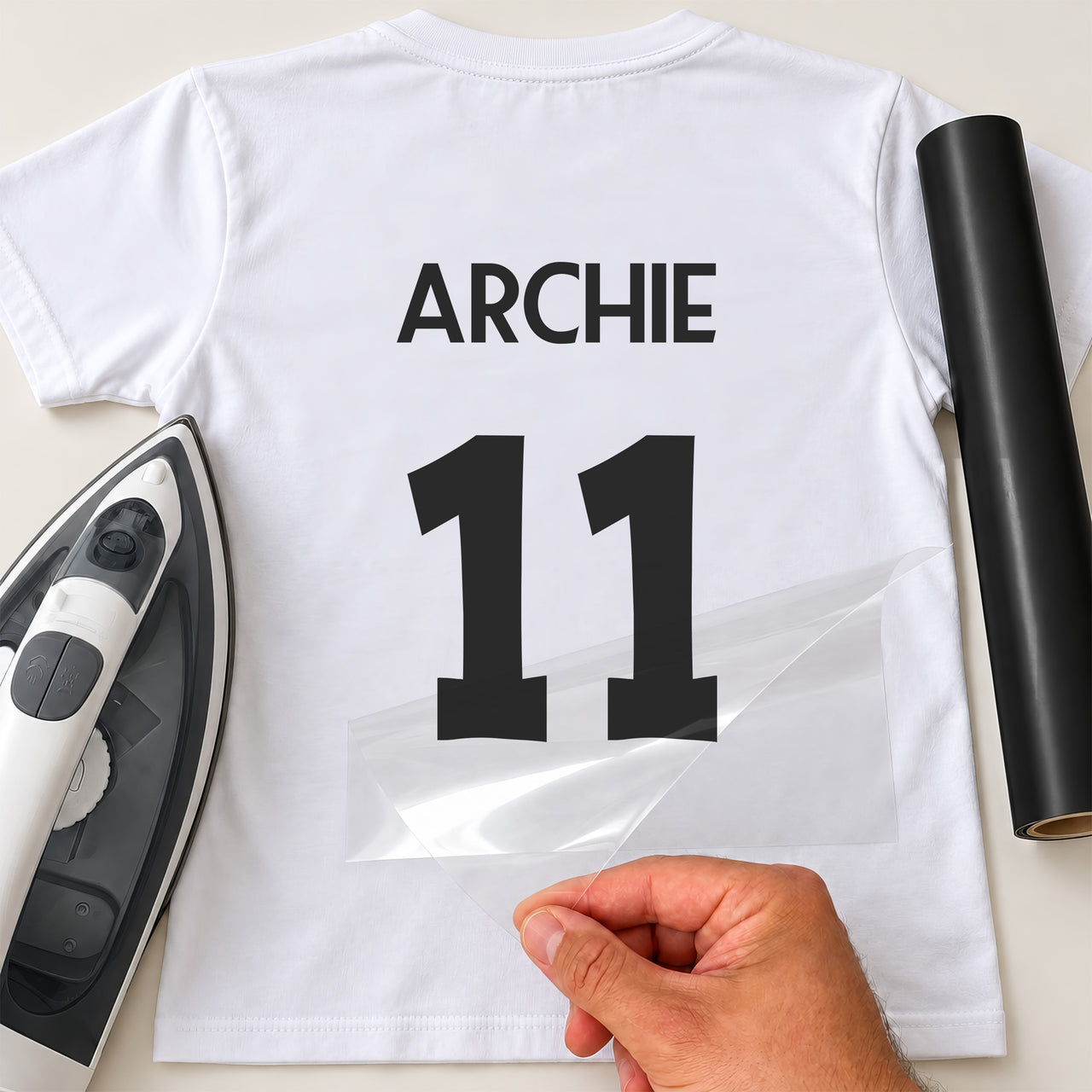 Running Club Vest Name Number iron-on transfer: black ARCHIE 11 on a white T-shirt, film being peeled