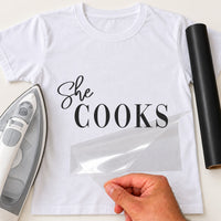 She Cooks iron-on transfer: black She COOKS on a white T-shirt, film being peeled