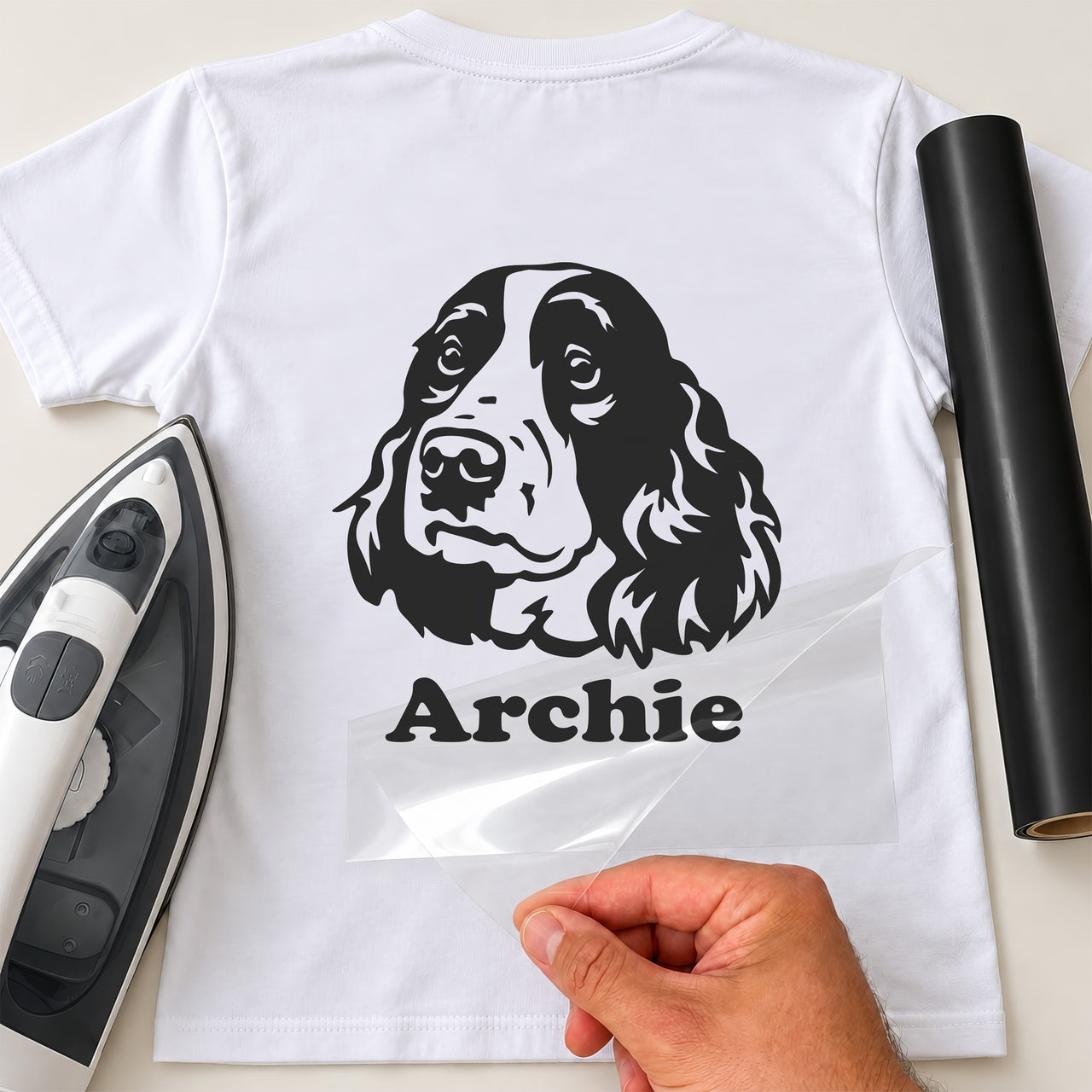 White T-shirt with black spaniel head portrait and 'Archie' name iron-on transfer, iron and black vinyl roll