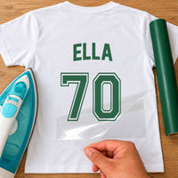 White T-shirt with green 'ELLA' and number '70' in jersey style, carrier film being peeled - iron-on vinyl transfer