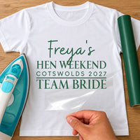 White tee with green 'Freya's Hen Weekend, Cotswolds 2027, Team Bride' in iron-on vinyl, film peeled back