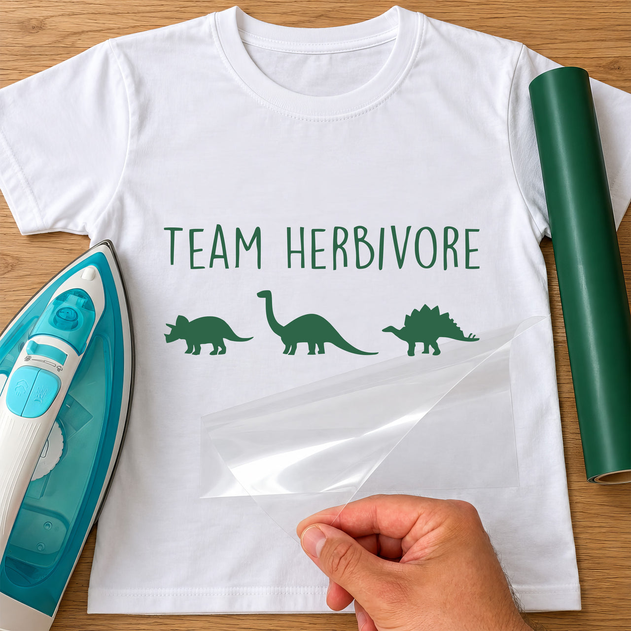 White T-shirt mockup with green 'Team Herbivore' iron-on vinyl and three plant-eating dinosaur silhouettes