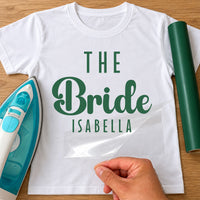 White T-shirt with green 'THE Bride ISABELLA', personalised bride iron-on transfer next to a green vinyl roll
