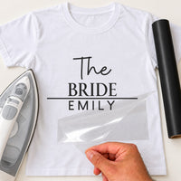 White T-shirt with black 'The BRIDE EMILY' transfer, script and serif lettering split by a line, film peeled away
