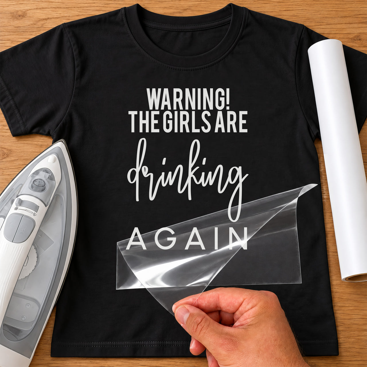 Black T-shirt with white 'WARNING! THE GIRLS ARE drinking AGAIN' iron-on transfer, iron and white vinyl roll