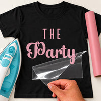 Black T-shirt with pink 'THE Party' iron-on vinyl transfer, carrier sheet being peeled off, iron and pink vinyl roll