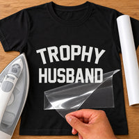Black T-shirt with white iron-on vinyl 'TROPHY HUSBAND' in bold varsity letters, iron and vinyl roll