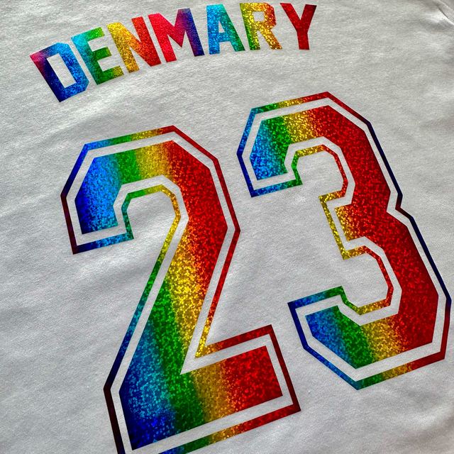 Rainbow metallic DENMARY 23 with a white outline on a white T-shirt